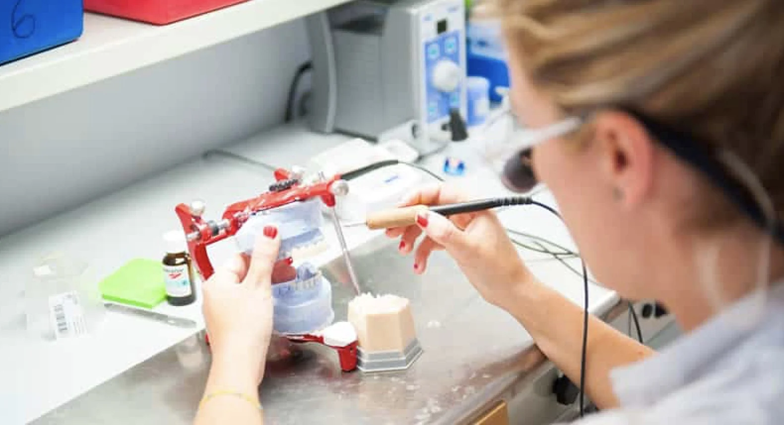 Técnica de laboratorio dental trabajando en una prótesis conectada con la clínica